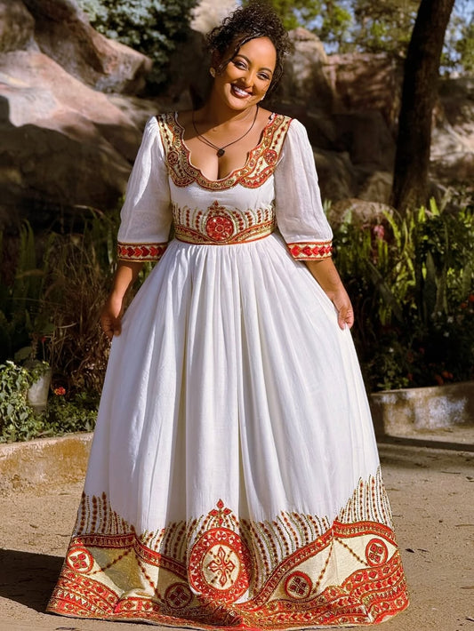 Woman wearing a white Ethiopian cultural dress with red and gold patterns outdoors.
