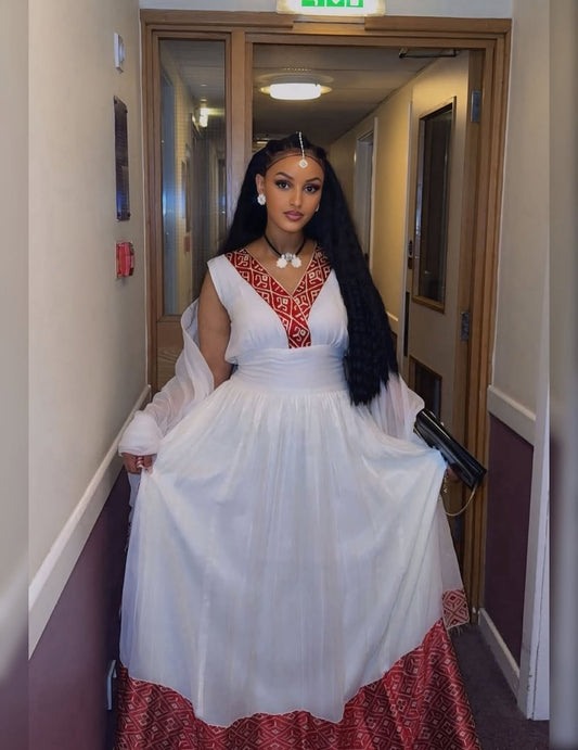 Woman in a white and red habesha kemis standing in a hallway