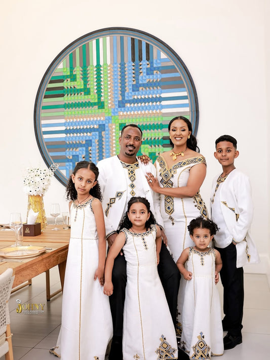 Family of six posing in Family Habesha Set together in front of a decorative mirror with geometric patterns.