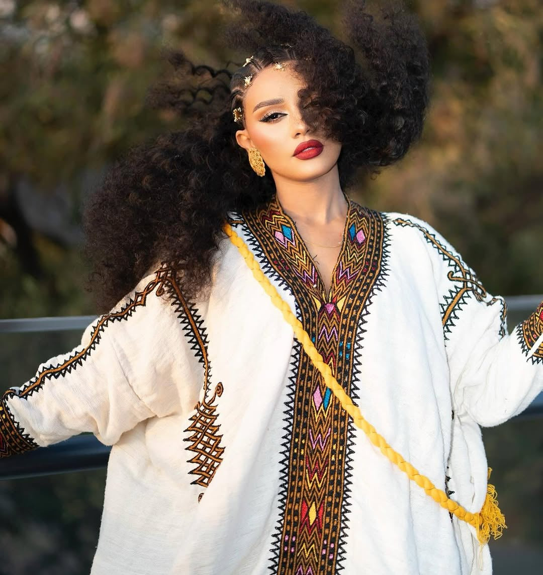 Woman wearing a traditional Ethiopian dress embroidered garment with a blurred natural background