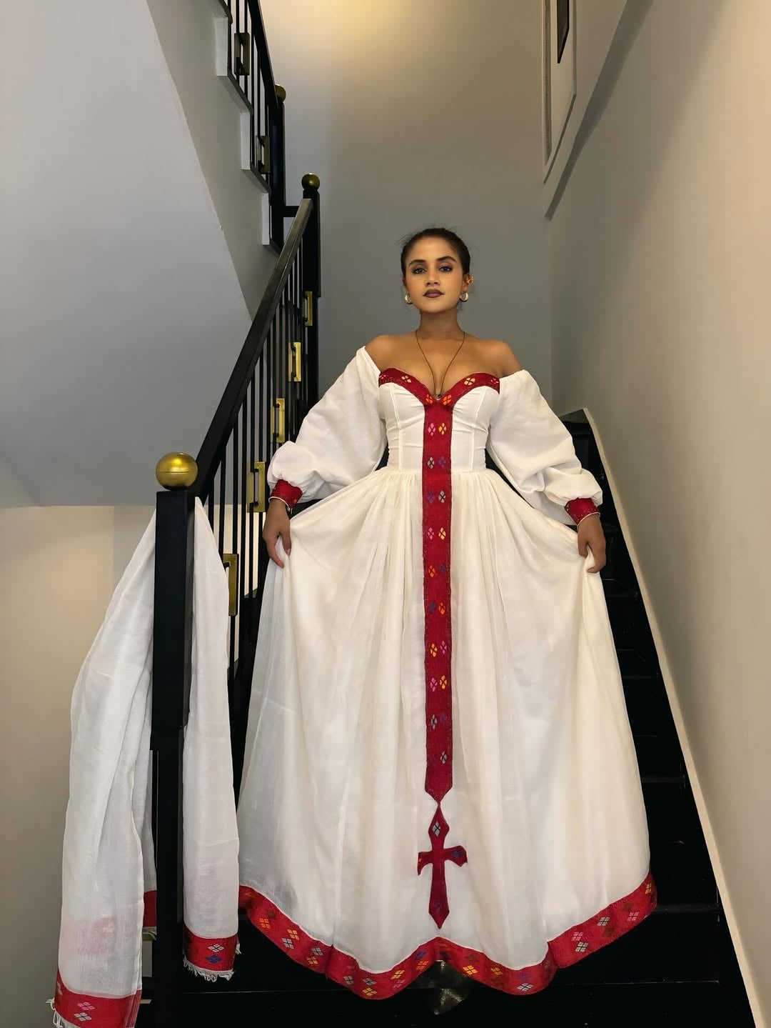 Woman in a white and red habesha dress standing on a staircase