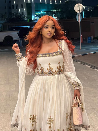 Woman in a white and gold traditional  Gold Habesha Zuria  with red hair on a city street.