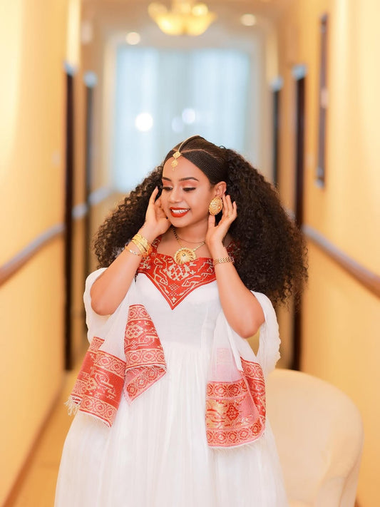 Woman in a white and Red Ethiopian Traditional Dress standing in a hallway.