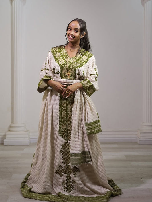 Woman wearing a Ethiopia traditional dress embroidered with green and white patterns in a studio setting.