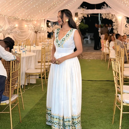 Woman in a Green Ethiopian dress with green and blue patterns at an outdoor event.