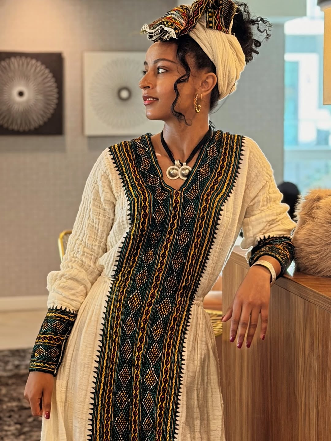 Woman wearing a traditional outfit with intricate patterns in an indoor setting