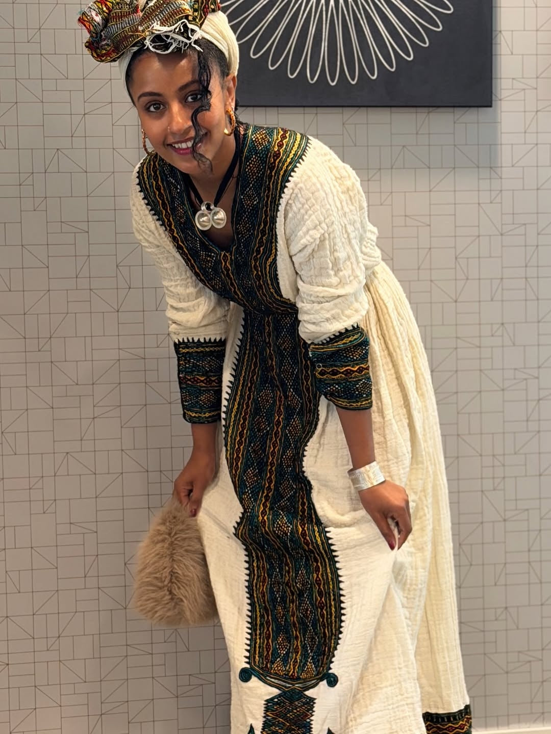 Woman in traditional attire posing against a tiled wall.