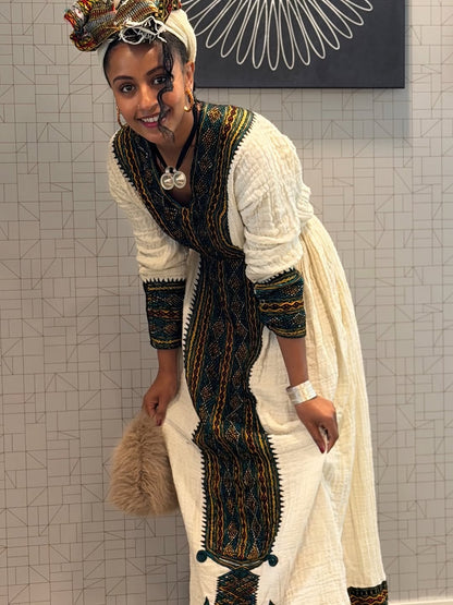 Woman in traditional attire posing against a tiled wall.