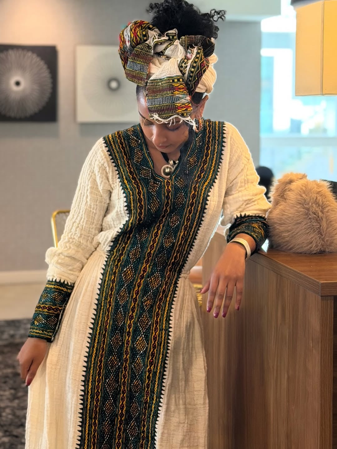 Person wearing a traditional outfit with intricate patterns in an indoor setting.