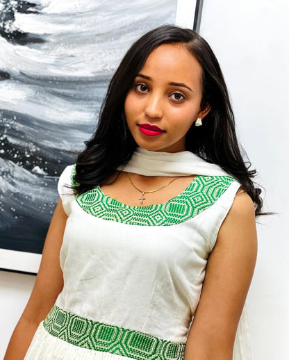 Woman wearing a white dress with green patterns in front of a painting