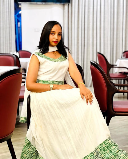 Woman in a white and green traditional outfit sitting in a restaurant.