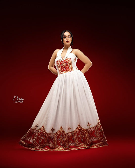 Woman wearing a  Ethiopian cultural dress  with red and gold embroidery on a red background