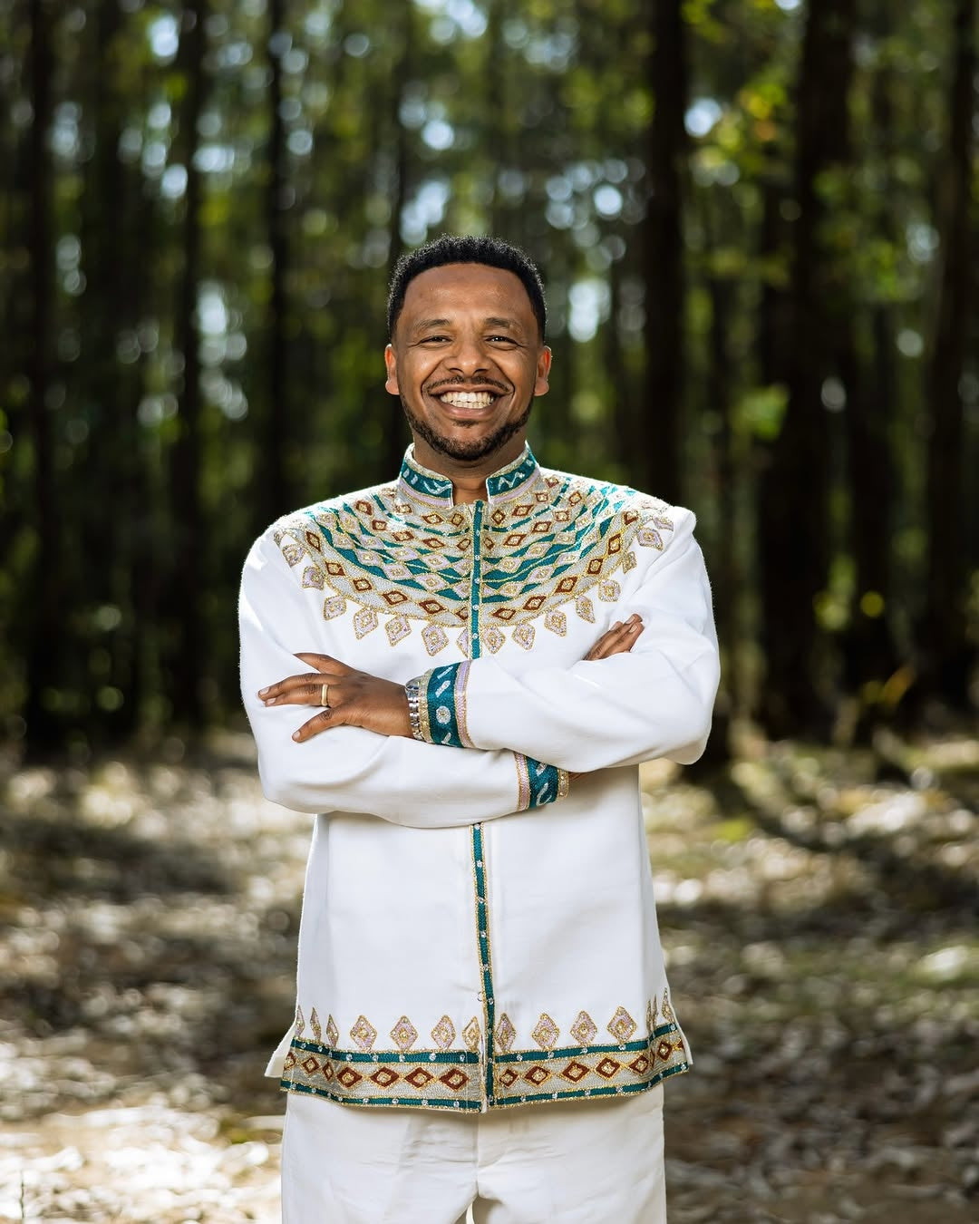 Man in traditional embroidered Green Habesha Wedding Couple Outfit standing in a forest