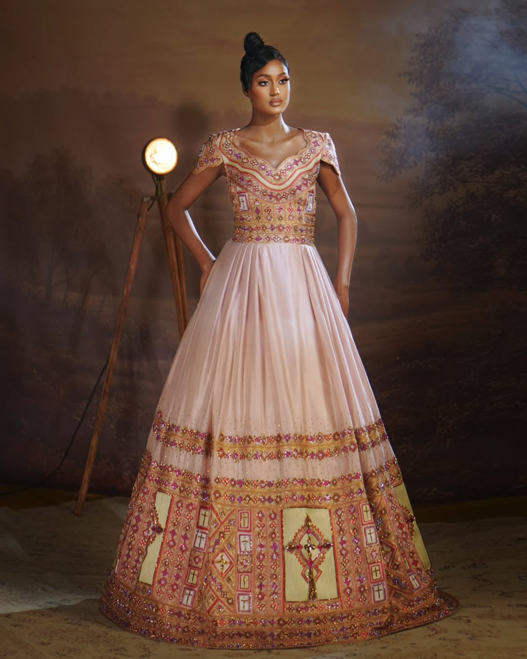 Woman wearing a traditional embroidered Habesha Outfit couple Set  in a studio setting with a warm light.
