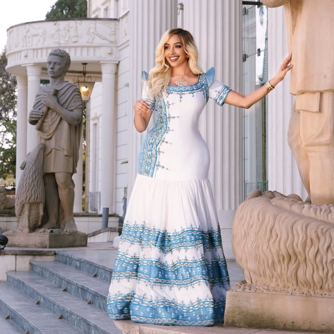 Woman in a white and blue habesha kemis standing in front of classical statues