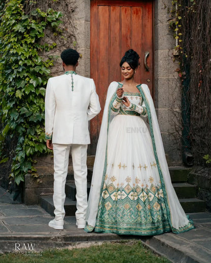 Man and woman in formal Habesha Outfit couple Set  standing in front of a wooden door with greenery.