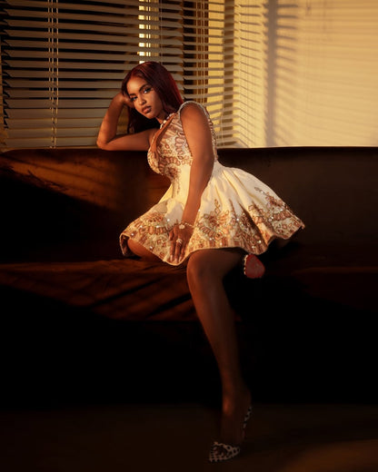 Woman in a patterned dress sitting on a couch with blinds casting shadows