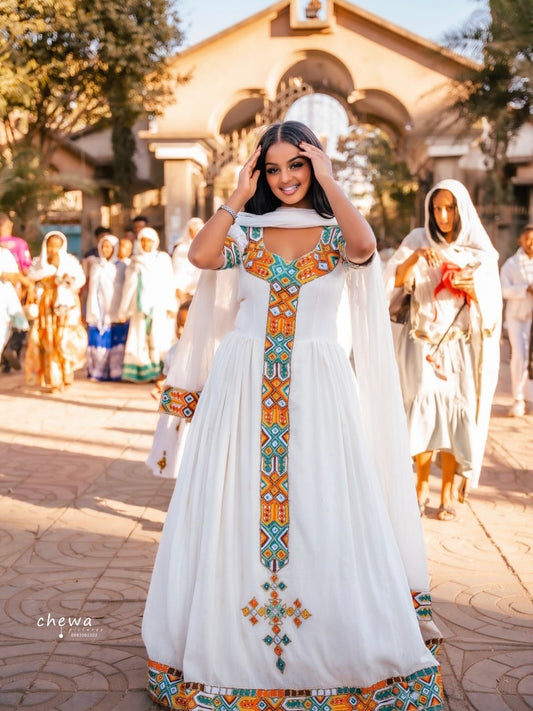 Woman in a Ethiopian Traditional Dress with colorful patterns standing outdoors.