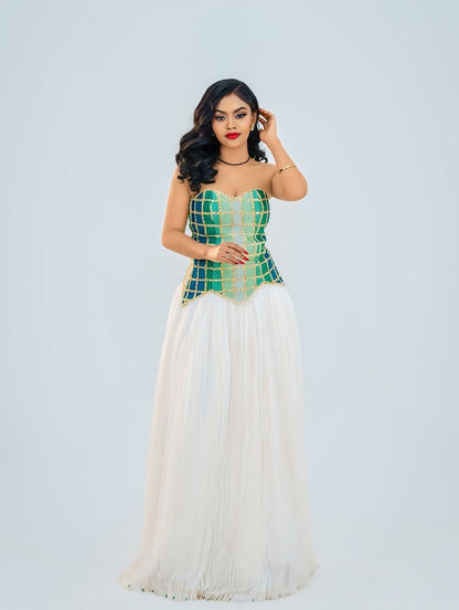 Woman wearing a green and white Ethiopian cultural dress against a light gray background