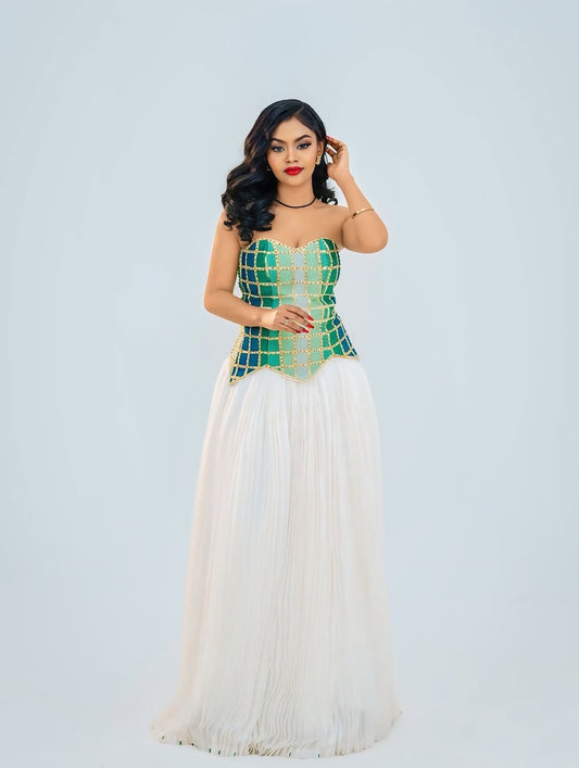 Woman wearing a green and white Ethiopian cultural dress against a light gray background