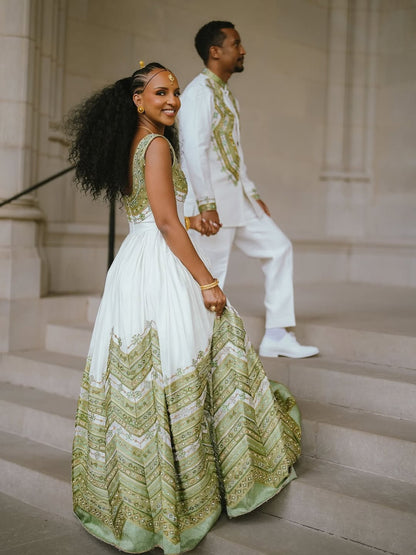 Woman in a green and white Habesha Outfit couple Set standing on steps with a man in formal attire.