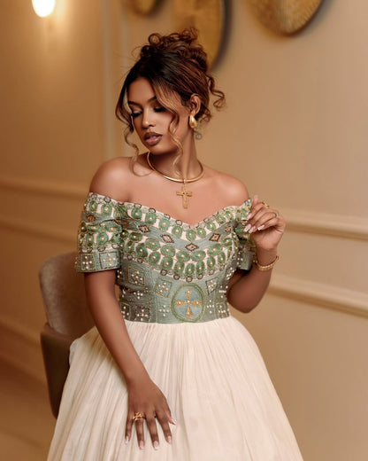 Woman wearing a green and white patterned Ethiopian traditional clothing in an elegant interior setting.