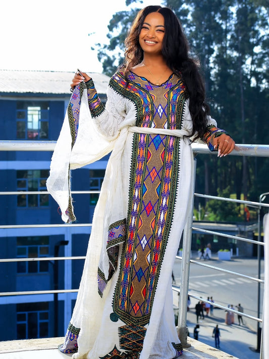 Woman wearing a colorful traditional Ethiopian outfit with a white background