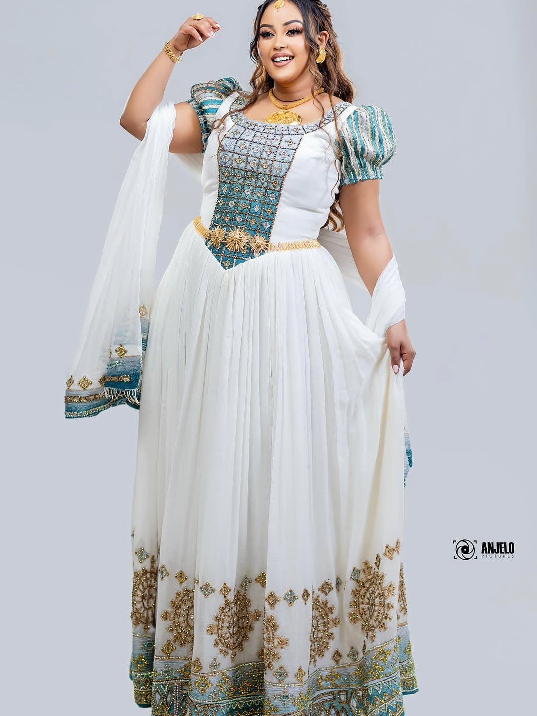 Woman wearing a white and blue embroidered dress with a plain background