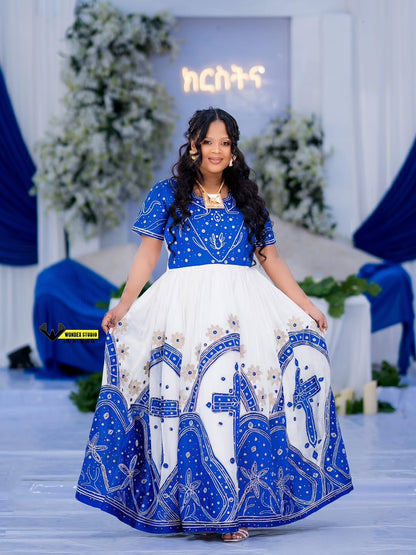 Woman wearing a blue and white Ethiopian traditional wedding dress with intricate patterns in a decorated indoor setting.