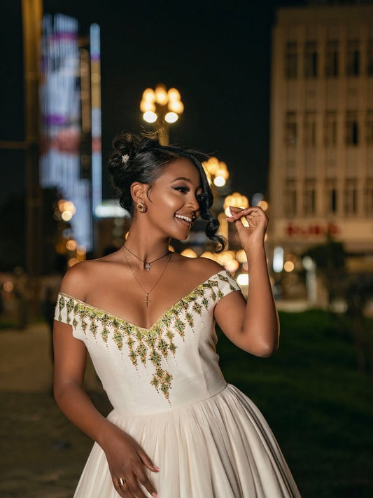 Woman in a white dress with green floral patterns at night in an urban setting