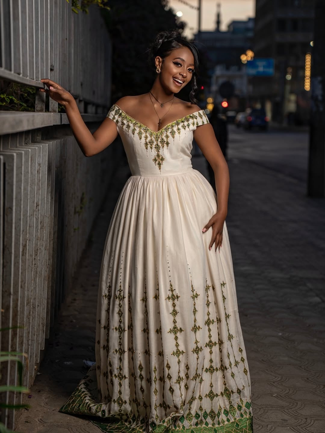 Woman in a white and gold habesha dress in an elegant interior setting.