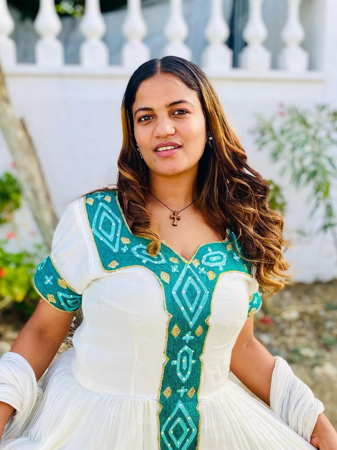 Woman wearing a traditional ethiopian kemis green and white design outdoors.