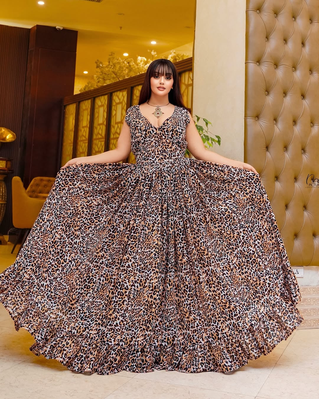 Woman in a leopard print Habesha Chiffon standing in an elegant interior setting.