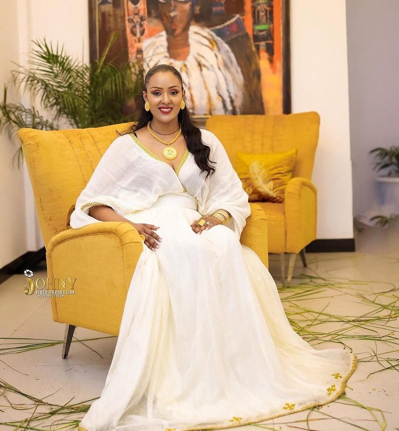 Gold Habesha dress in handwoven cotton featuring silver tilf embroidery for engagement ceremonies