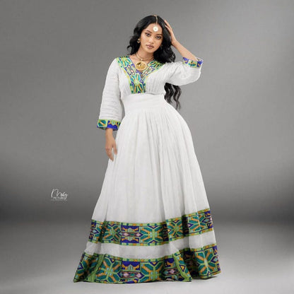 Woman wearing a green ethiopian cultural dress with colorful patterns on a gray background