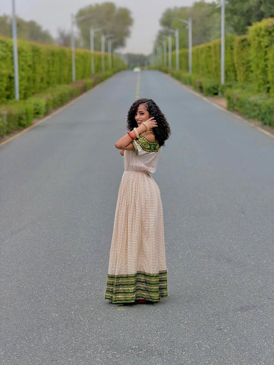 Woman in a long habesha dress  standing on a road with greenery on either side