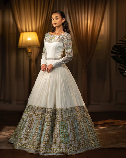 Woman wearing a white and Green Habesha Libs  in a warm-toned room.
