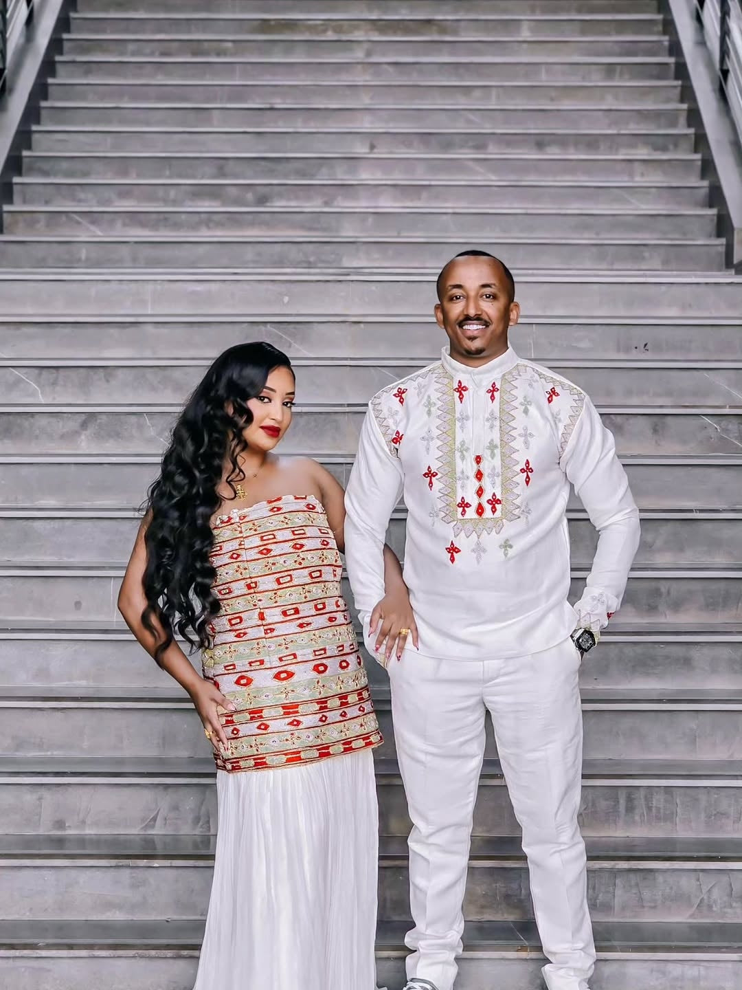 Man and woman in Habesha Couple Matching Set attire standing on a staircase