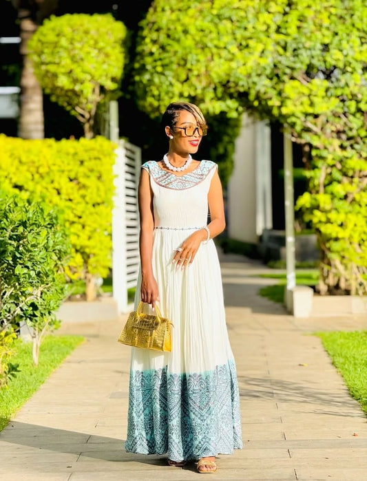 Woman in a white and blue dress standing on a path with greenery around