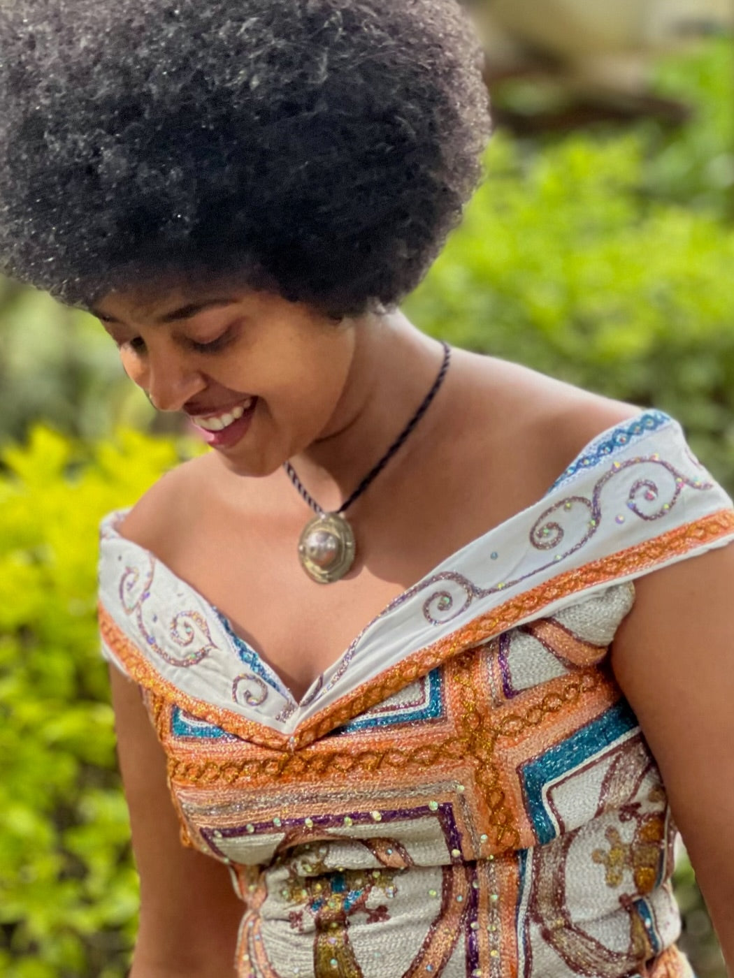 Woman wearing a colorful embroidered dress with a blurred green background