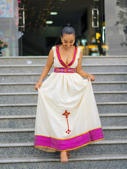Woman in a traditional white and Purple Accent Habesha Zuriastanding on steps outdoors.