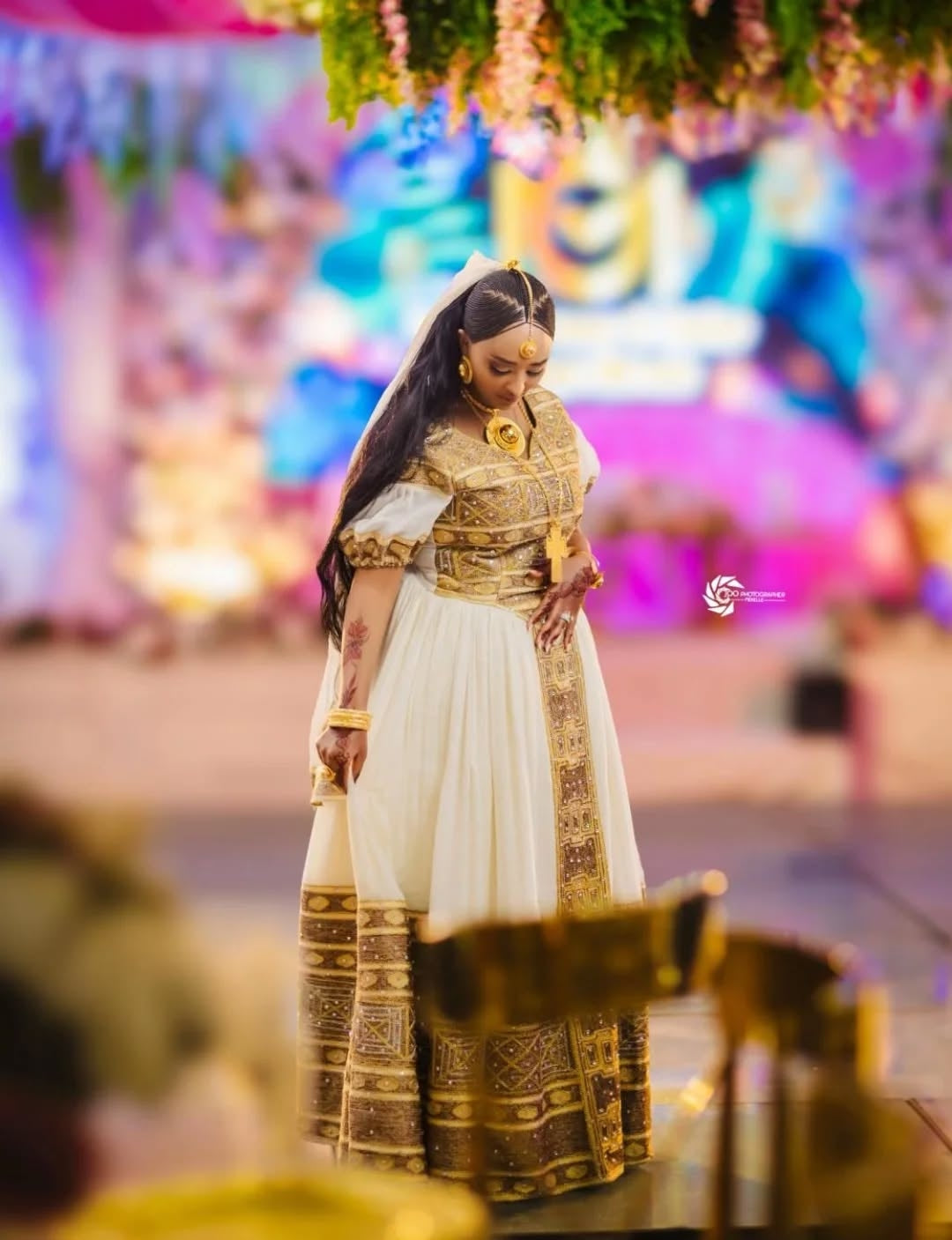 Woman in Ethiopian kemis attire with a colorful background