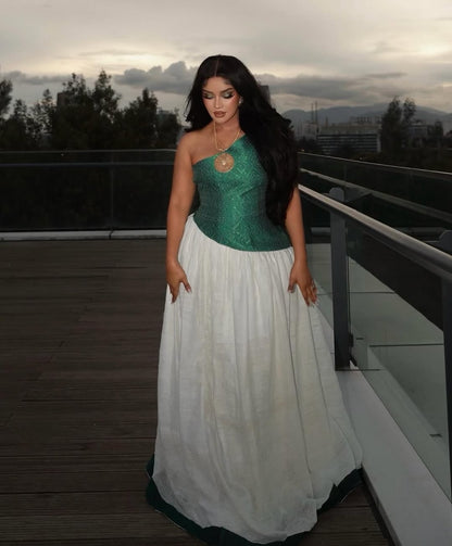 Woman in a green and white Habesha Dress – standing on a rooftop with cityscape in the background