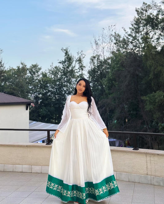 Woman wearing a white Ethiopian Clothing  with green hem in an outdoor setting
