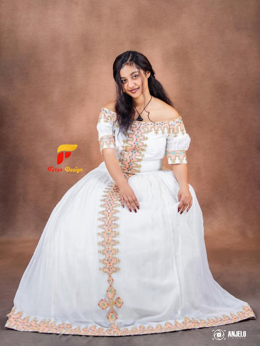 Woman wearing a white off-shoulder in with gold embroidery on a brown backround
