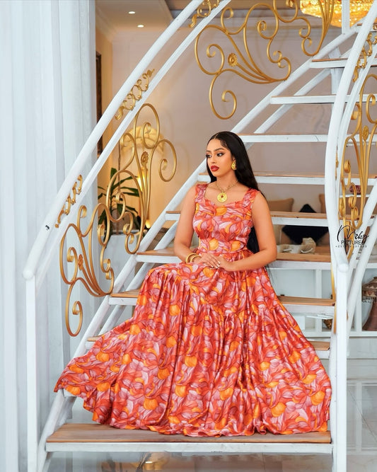 Woman in a red and orange patterned Habesha Chiffon Dress sitting on a decorative staircase.
