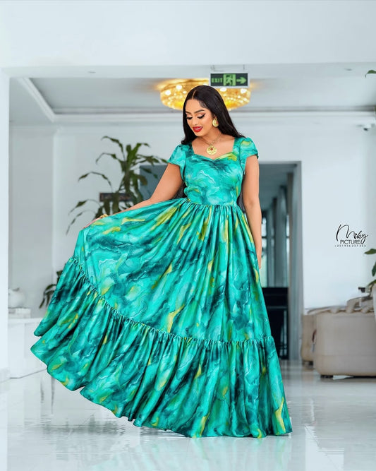 Woman in a teal dress with yellow patterns in an indoor setting