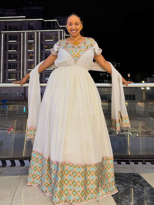 Woman in a Ethiopian Traditional Dress with geometric patterns standing on a rooftop at night.