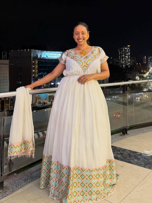 Woman in a Ethiopian Traditional Dress with geometric patterns standing on a rooftop at night.