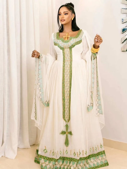 Woman wearing a white and green traditional Habesha Kemis with cross designs.